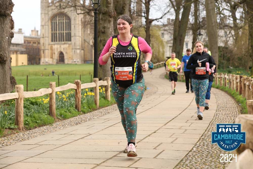 Me looking determined as I run past King's College. I'm wearing running gear; leggings with highland cows, my club vest, a bright pink top and a race number.